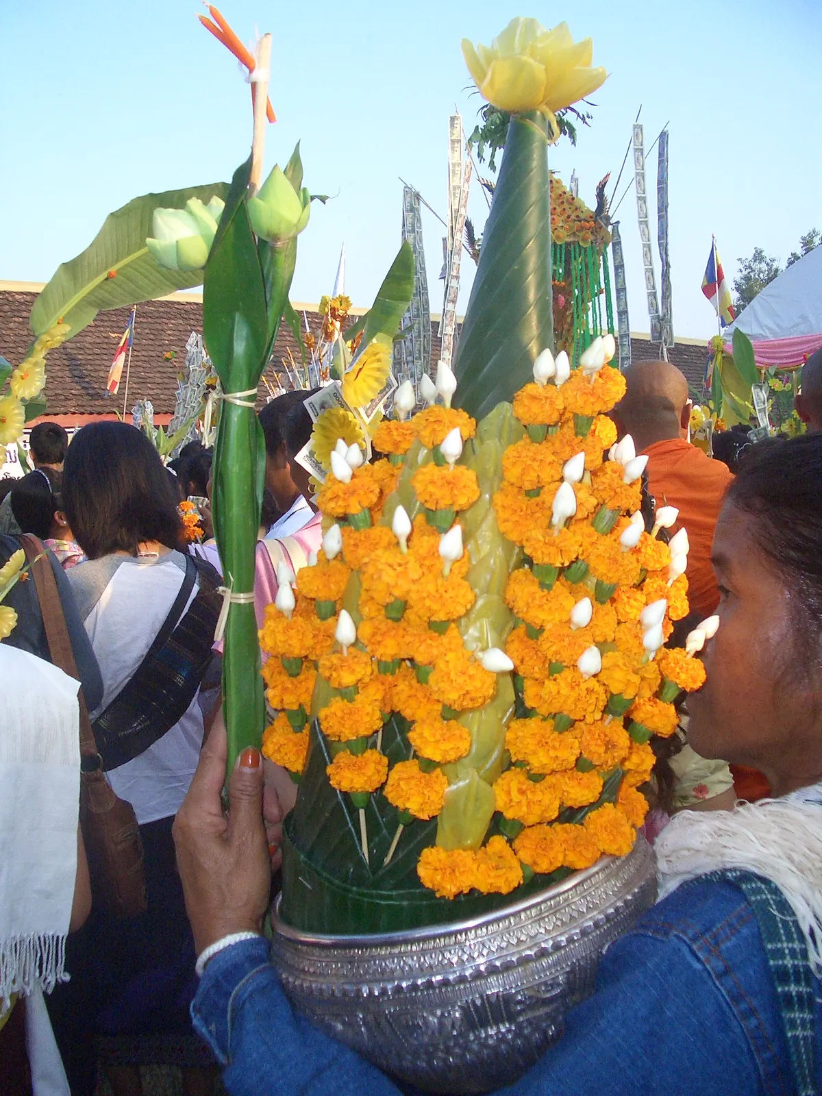Offerte di fiori durante il tak bat del Boun That Luang Offerte di fiori di calendula e ceri tra i pellegrini durante il tak bat del Boun That Luang a Vientiane