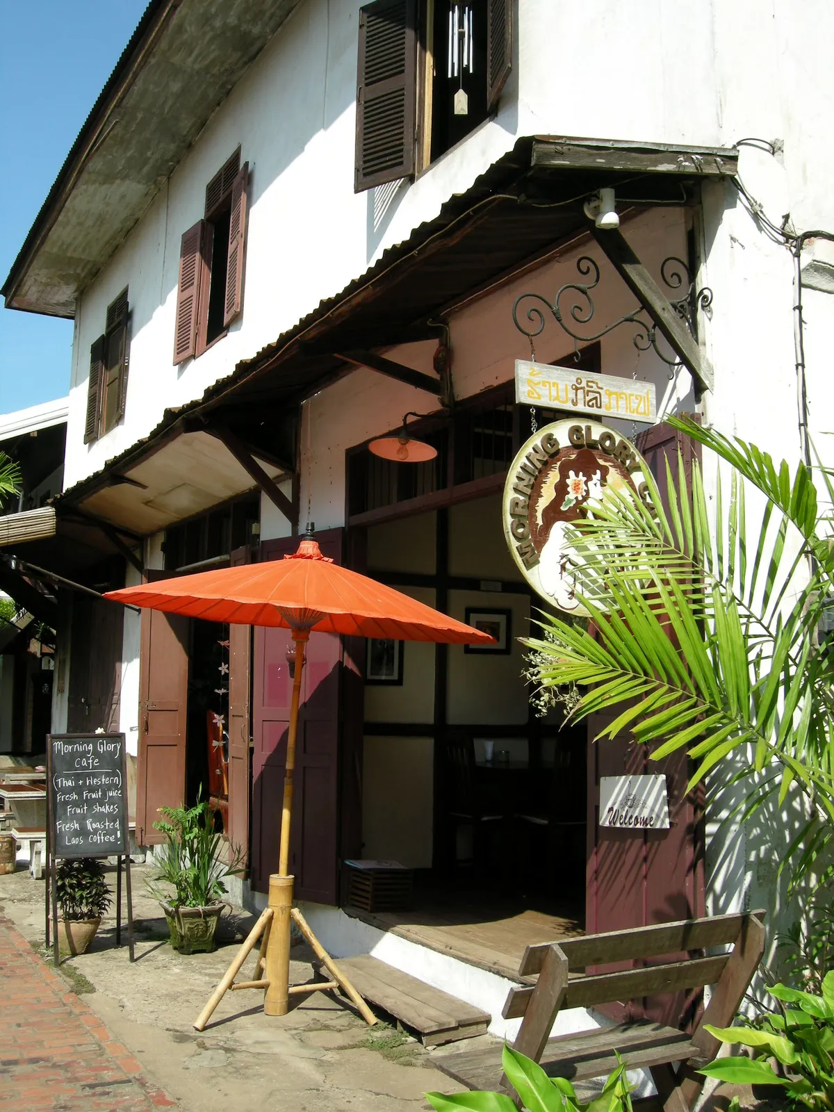 Caffetteria tipica nel centro storico di Luang Prabang con tavolini all'aperto e insegna di legno