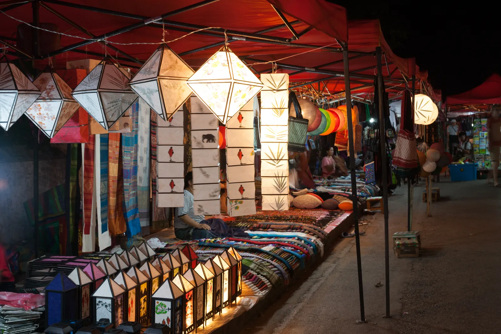 Bancarella di lanterne di carta e tessuti colorati al mercato notturno di Luang Prabang