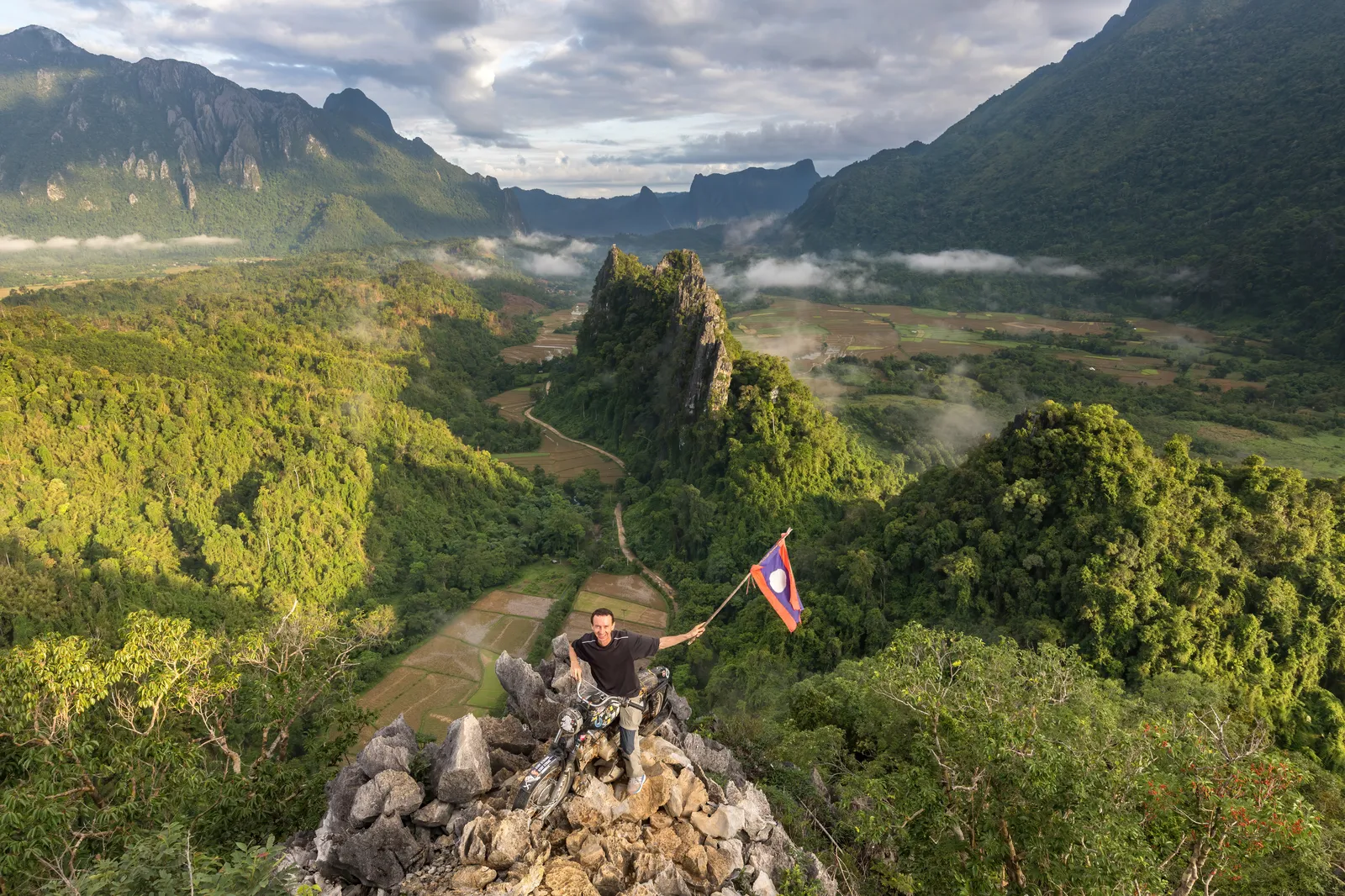 Motociclista con la bandiera del Laos sulla cima del monte Nam Xay, a Vang Vieng