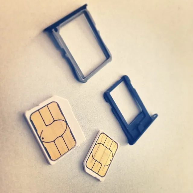 SIM card in formato nano e micro accanto ai carrelli di espulsione metallici di uno smartphone