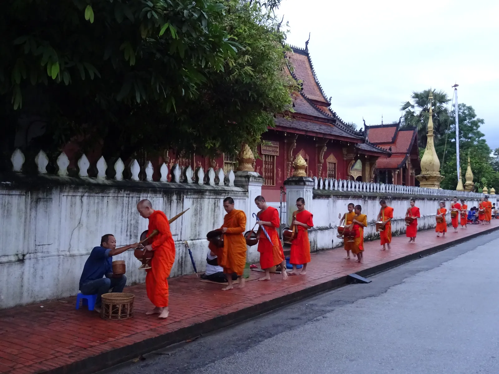Cerimonia del Tak Bat all'alba a Luang Prabang: monaci buddisti in fila ricevono il riso dai fedeli davanti a un tempio