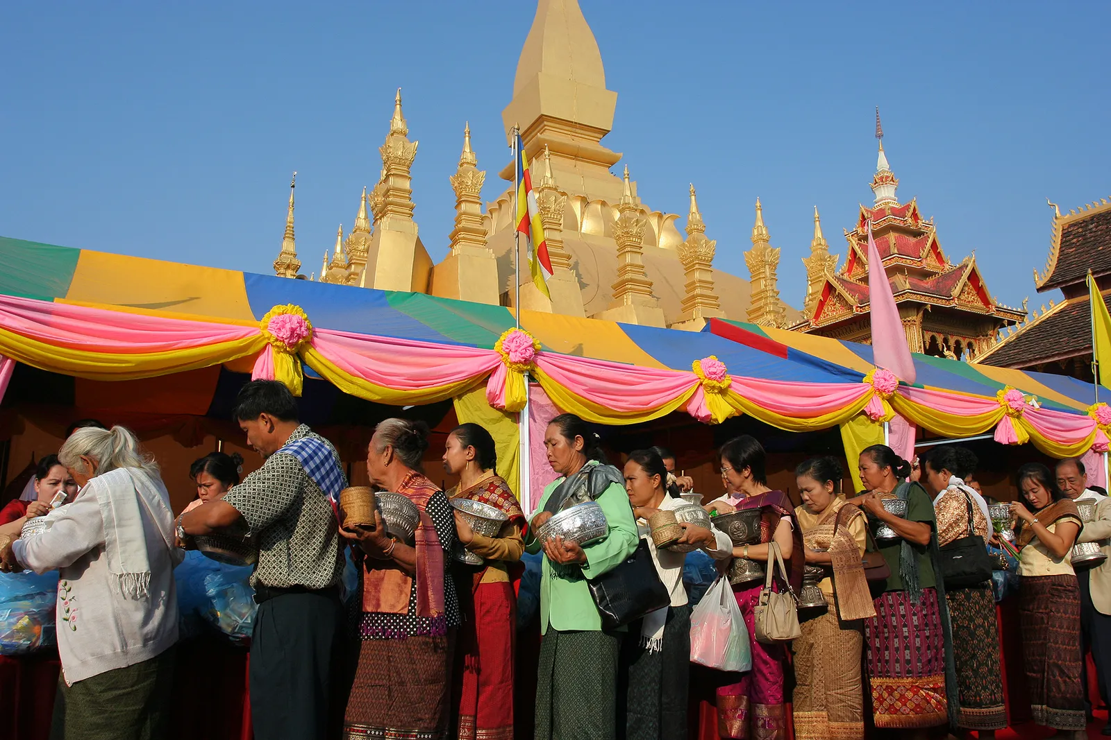 that-luang-festival-vientiane-laos Fedeli in abiti tradizionali con offerte davanti allo stupa dorato di Pha That Luang durante il Boun That Luang a Vientiane