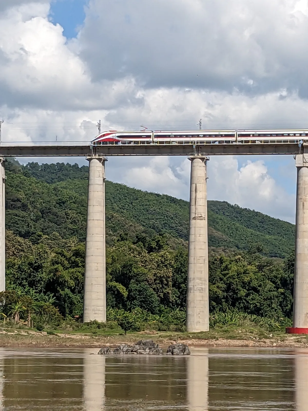 Treno ad alta velocità attraversa la campagna laotiana tra montagne e risaie
