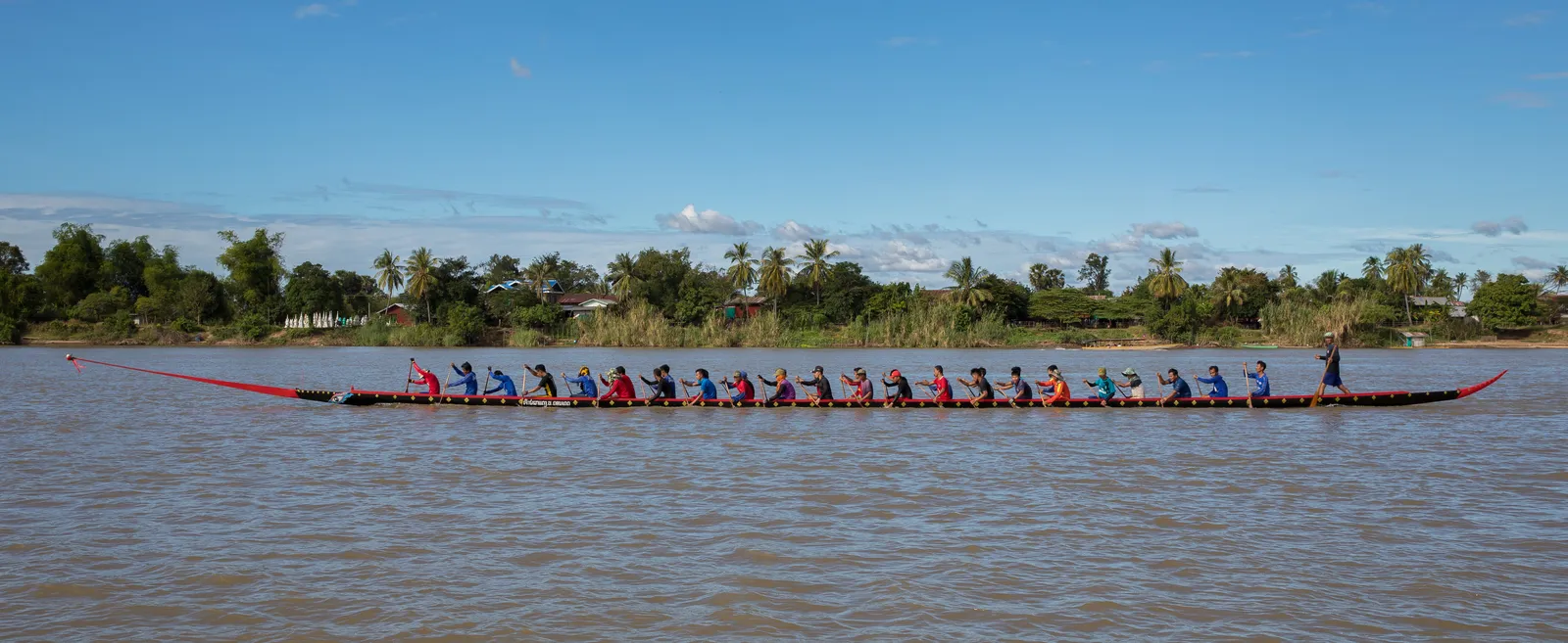 Longboat con equipaggio da competizione sul Mekong Longboat da competizione con trentacinque vogatori in fila sulle acque del Mekong in Laos