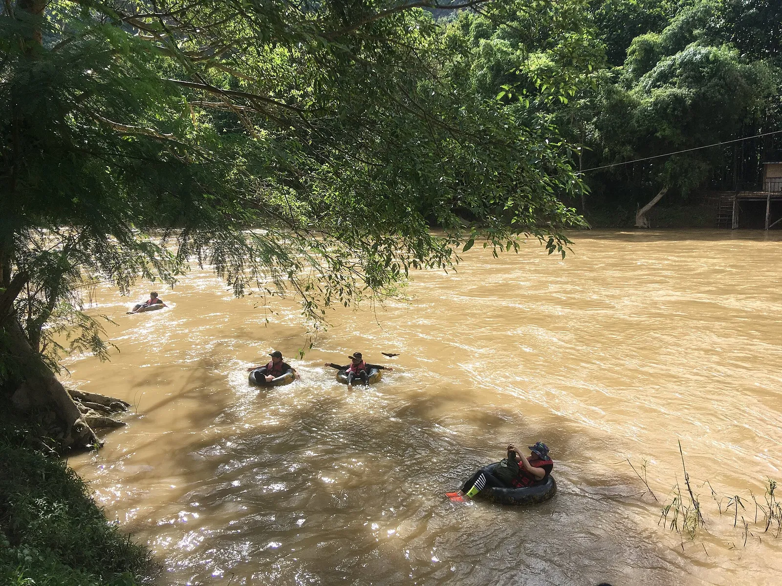 Tubing di gruppo sul Nam Song Gruppo di turisti in tubing con giubbotti salvagente sul fiume Nam Song a Vang Vieng
