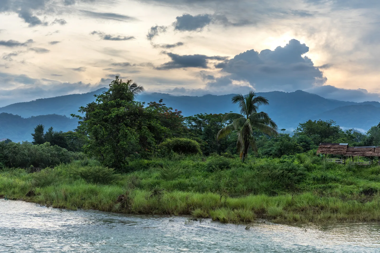 Il fiume Nam Song e le montagne carsiche di Vang Vieng all'alba con nuvole arancio riflesse sull'acqua